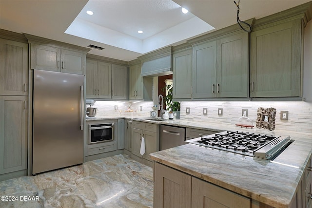 kitchen featuring kitchen peninsula, sink, a raised ceiling, backsplash, and appliances with stainless steel finishes