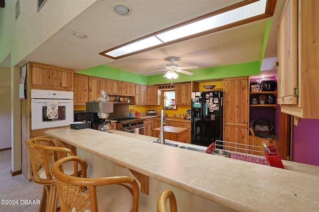 kitchen featuring oven, black fridge, a breakfast bar, and kitchen peninsula