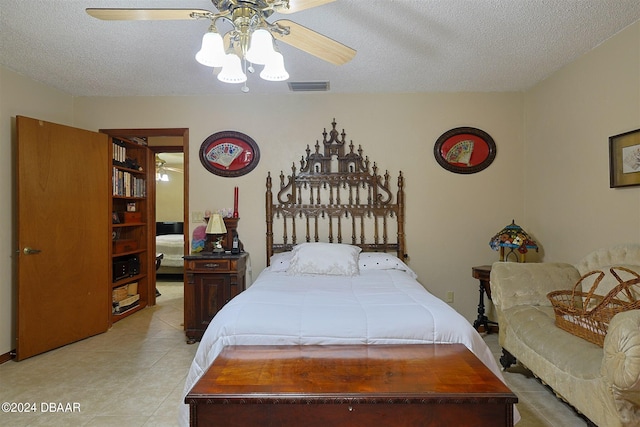 bedroom with a textured ceiling, light tile patterned floors, and ceiling fan