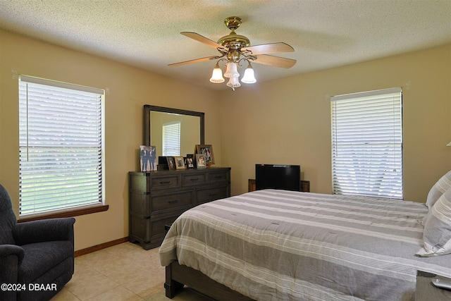 tiled bedroom with a textured ceiling and ceiling fan