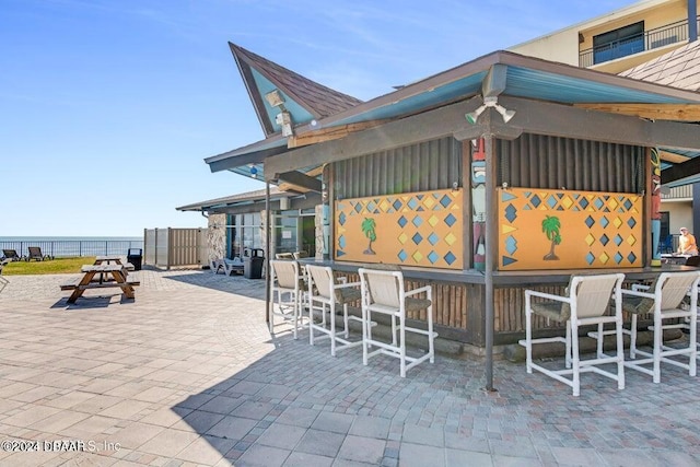 view of patio with a water view and a bar