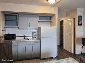 kitchen with gray cabinets, sink, white fridge, and hardwood / wood-style floors