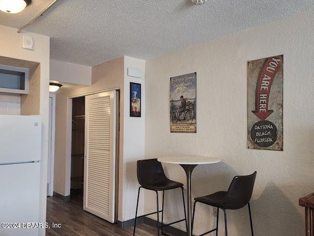 dining room featuring dark wood-type flooring and a textured ceiling