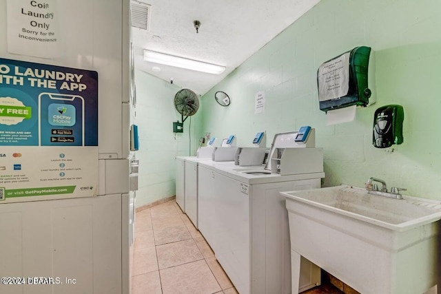 clothes washing area with washer and dryer, light tile patterned flooring, and sink