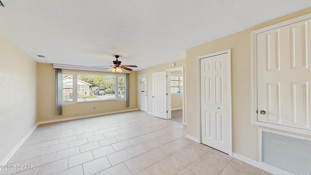 spare room with visible vents, ceiling fan, baseboards, and light tile patterned floors