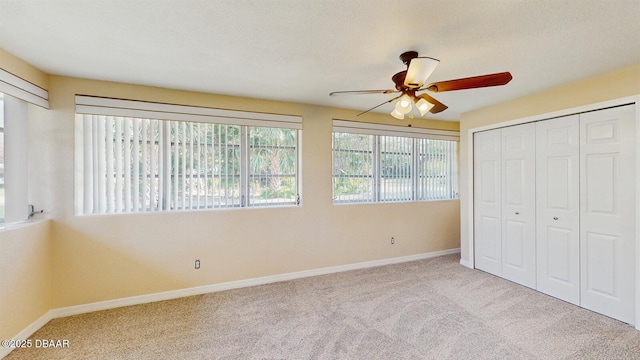 unfurnished bedroom with a closet, carpet, a ceiling fan, and baseboards