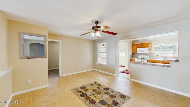 interior space featuring light tile patterned floors, white appliances, a sink, baseboards, and decorative backsplash