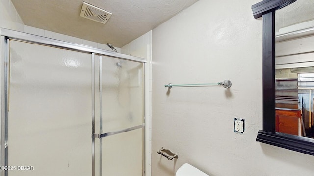 full bathroom featuring a textured ceiling, an enclosed shower, and visible vents