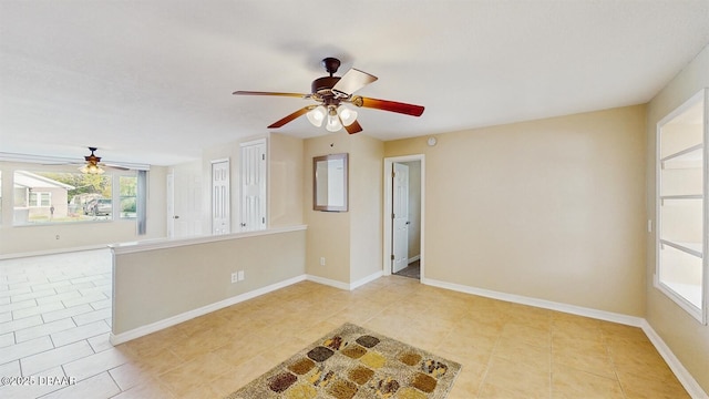 empty room featuring a ceiling fan, baseboards, and light tile patterned floors