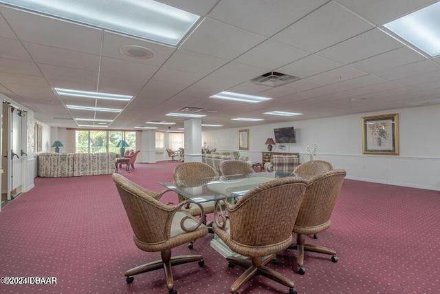 carpeted dining space with a paneled ceiling