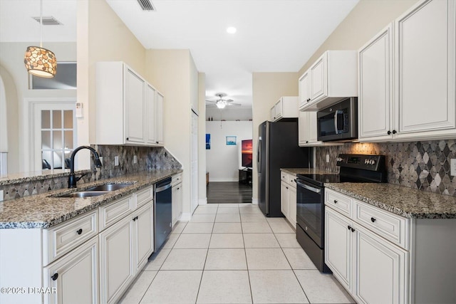 kitchen with white cabinetry, stainless steel appliances, sink, and dark stone countertops