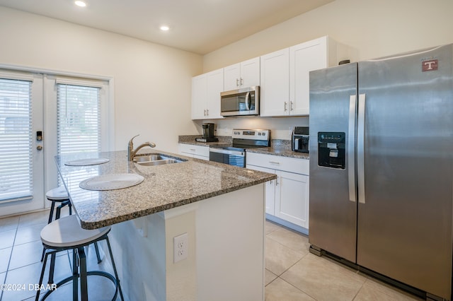 kitchen featuring stainless steel appliances, white cabinets, sink, a breakfast bar area, and a kitchen island with sink