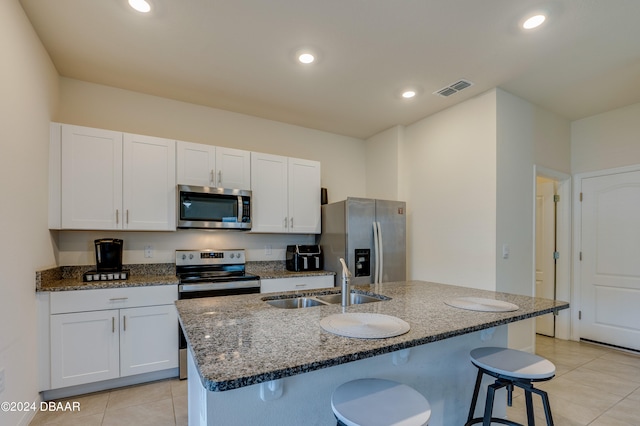 kitchen with a center island with sink, white cabinetry, appliances with stainless steel finishes, sink, and a breakfast bar area