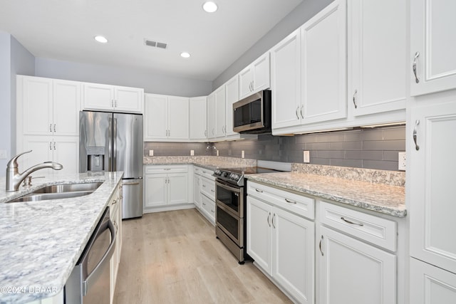 kitchen featuring light wood finished floors, visible vents, appliances with stainless steel finishes, white cabinetry, and a sink