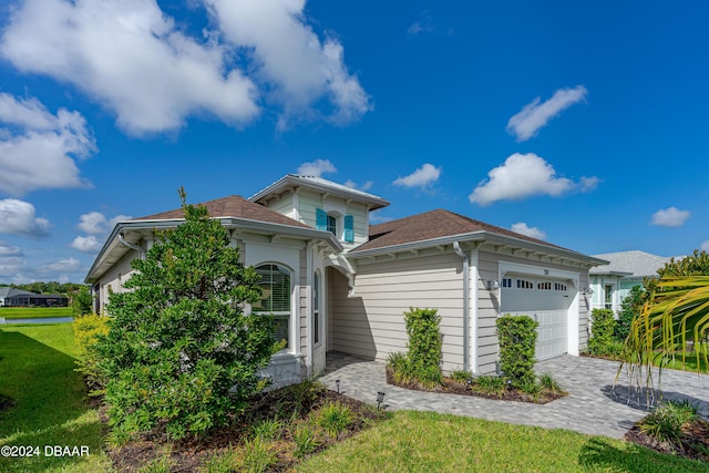 view of front of property with a front lawn, decorative driveway, and an attached garage