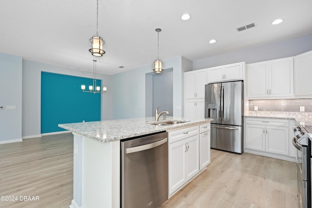 kitchen featuring light wood finished floors, appliances with stainless steel finishes, a sink, and a kitchen island with sink