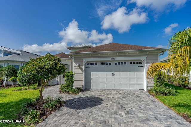 view of front of home with a garage, a front lawn, and decorative driveway