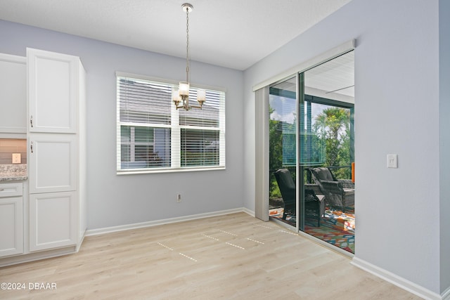 unfurnished dining area with light wood-style floors, baseboards, and a chandelier