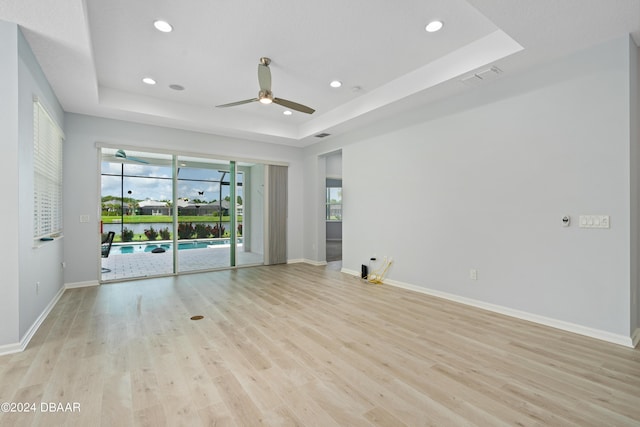 unfurnished room with light wood-style floors, a tray ceiling, and visible vents