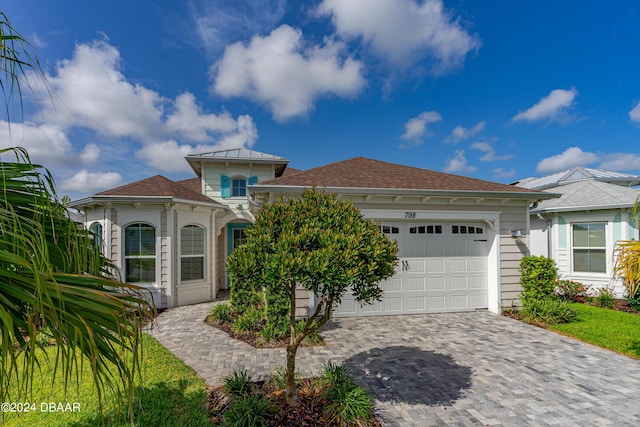 view of front of property featuring roof with shingles, decorative driveway, and an attached garage