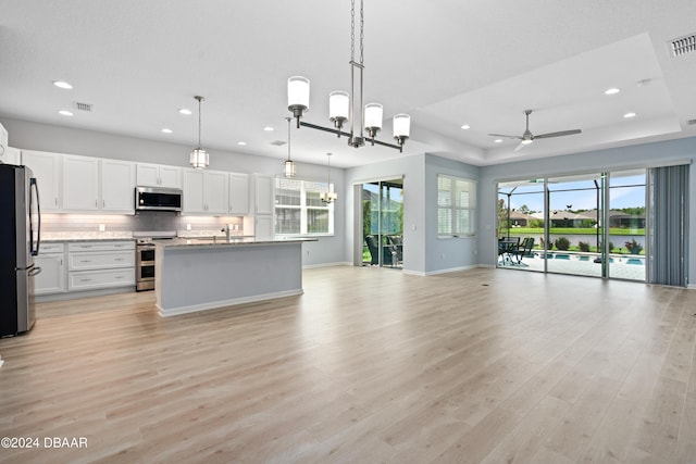 kitchen with light wood finished floors, visible vents, appliances with stainless steel finishes, open floor plan, and ceiling fan with notable chandelier