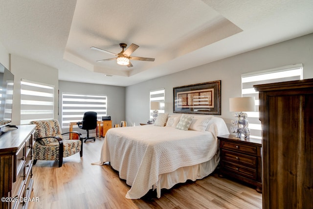 1245 Hampstead Ln, Ormond Beach, FL 32174 - bedroom with a tray ceiling, light wood finished floors, an office area, and a ceiling fan