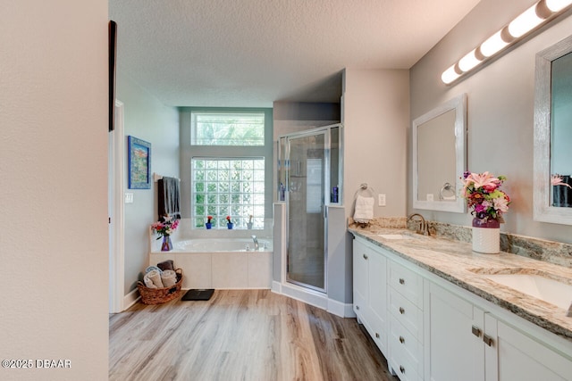 1245 Hampstead Ln, Ormond Beach, FL 32174 - bathroom featuring double vanity, a textured ceiling, a garden tub, a shower stall, and wood finished floors