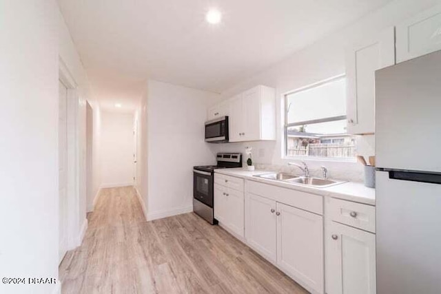 kitchen featuring white cabinets, sink, light wood-type flooring, and appliances with stainless steel finishes