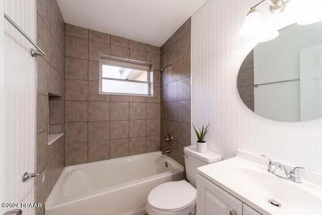 full bathroom featuring vanity, tiled shower / bath combo, and toilet