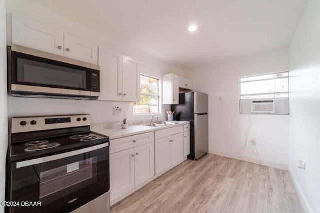 kitchen with cooling unit, appliances with stainless steel finishes, light hardwood / wood-style floors, and white cabinets