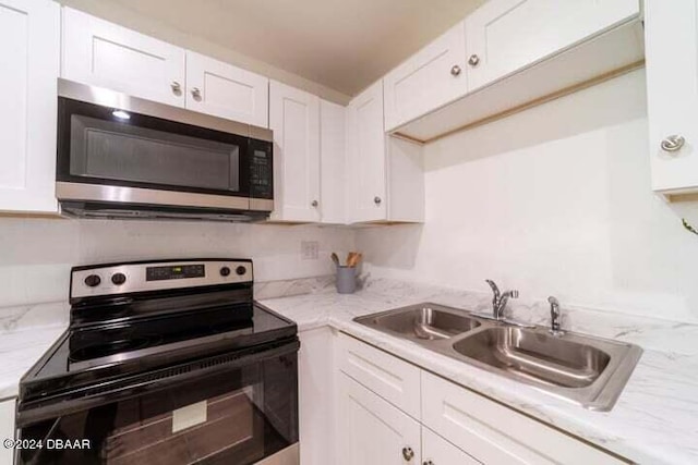 kitchen with stainless steel appliances, light stone counters, white cabinets, sink, and tasteful backsplash