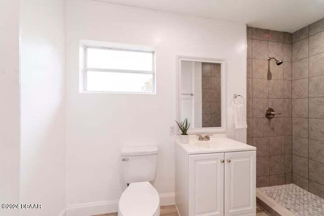 bathroom featuring tiled shower, toilet, and vanity