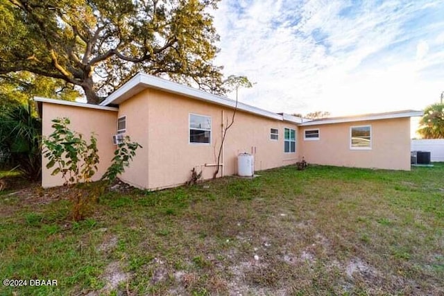 back of house with cooling unit and a yard