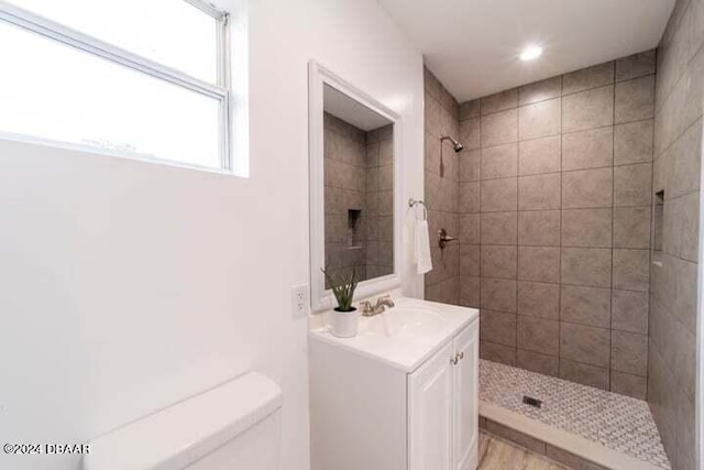 bathroom with toilet, vanity, and a tile shower