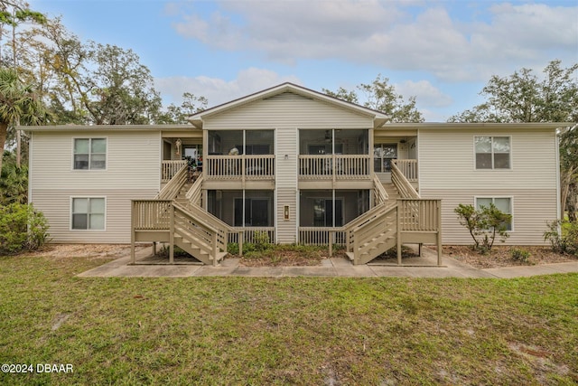 back of property featuring a sunroom and a lawn