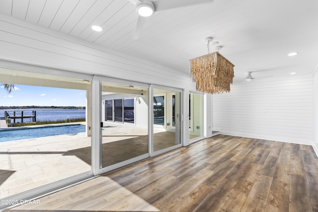 unfurnished sunroom featuring ceiling fan and a water view