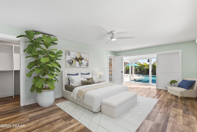 bedroom featuring ceiling fan, wood-type flooring, a spacious closet, access to outside, and a closet