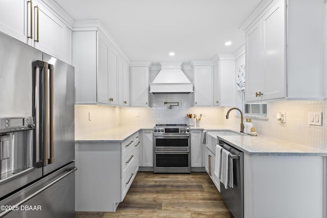 kitchen featuring appliances with stainless steel finishes, dark hardwood / wood-style floors, custom range hood, white cabinets, and backsplash