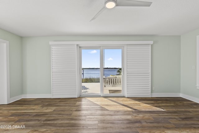 spare room with a textured ceiling, dark hardwood / wood-style floors, ceiling fan, and a water view