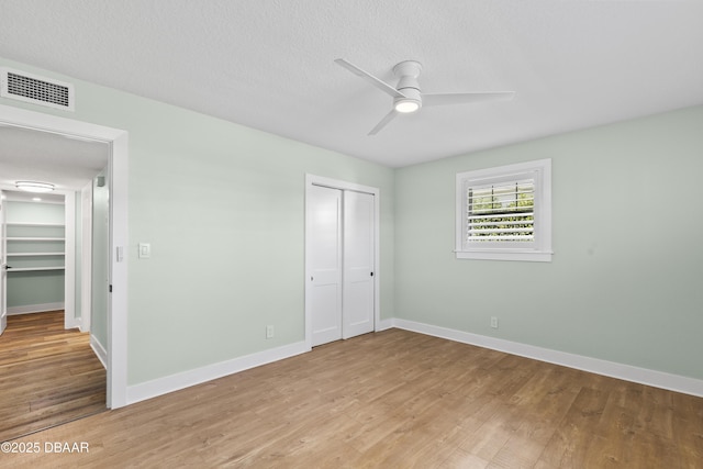 unfurnished bedroom featuring a textured ceiling, light hardwood / wood-style flooring, a closet, and ceiling fan