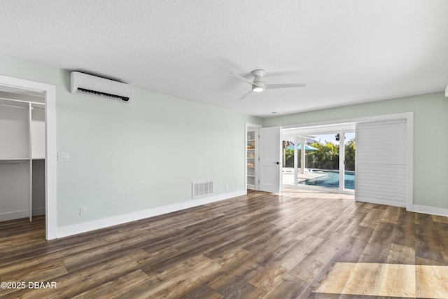 interior space featuring ceiling fan, dark hardwood / wood-style floors, a textured ceiling, and an AC wall unit