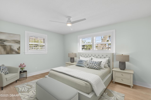 bedroom featuring multiple windows, light hardwood / wood-style floors, and ceiling fan