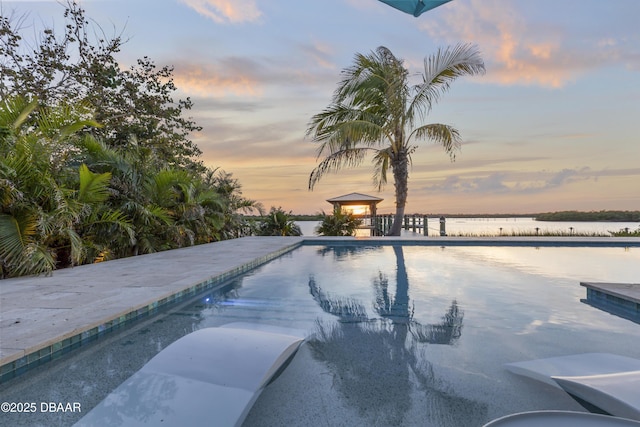 pool at dusk featuring a water view