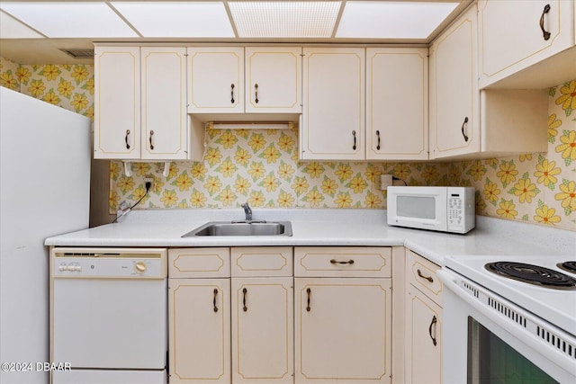 kitchen with white appliances, sink, and cream cabinetry