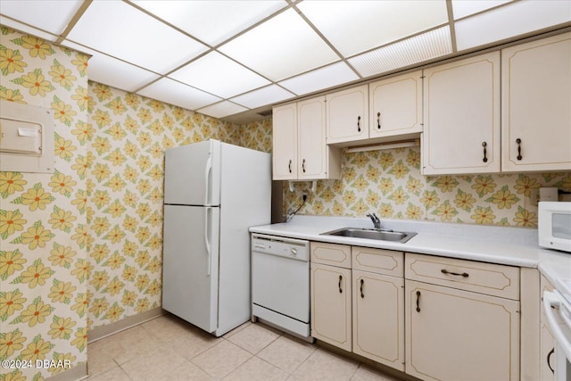 kitchen with white appliances, cream cabinetry, a paneled ceiling, and sink