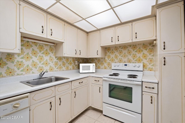 kitchen featuring light tile patterned floors, white appliances, cream cabinetry, and sink