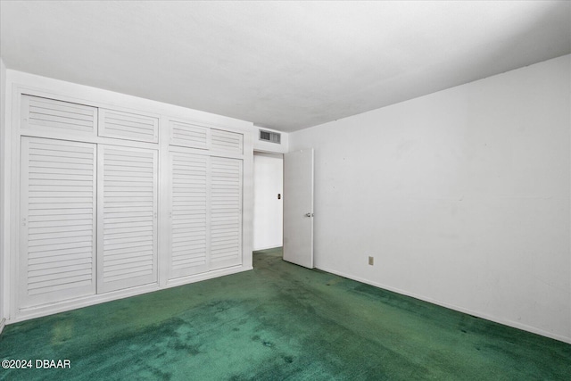 unfurnished bedroom featuring dark colored carpet and a closet