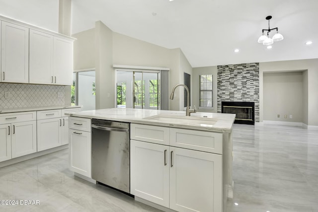 kitchen with decorative backsplash, a tiled fireplace, dishwasher, white cabinetry, and a sink