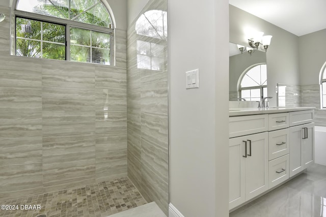 full bathroom featuring marble finish floor, tiled shower, and vanity