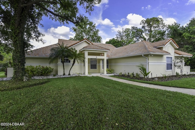 mediterranean / spanish-style home featuring stucco siding, a tiled roof, and a front yard